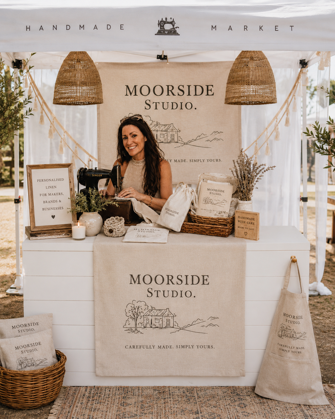 Laura at the Moorside Studio market stall with branded linen runner, banner and apron